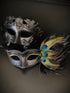 Couples mask set with a black gladiator mask for the man and a black peacock mask with gold glitter eyes.