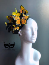 Orange monarch butterflies on top of a black fascinator hat.