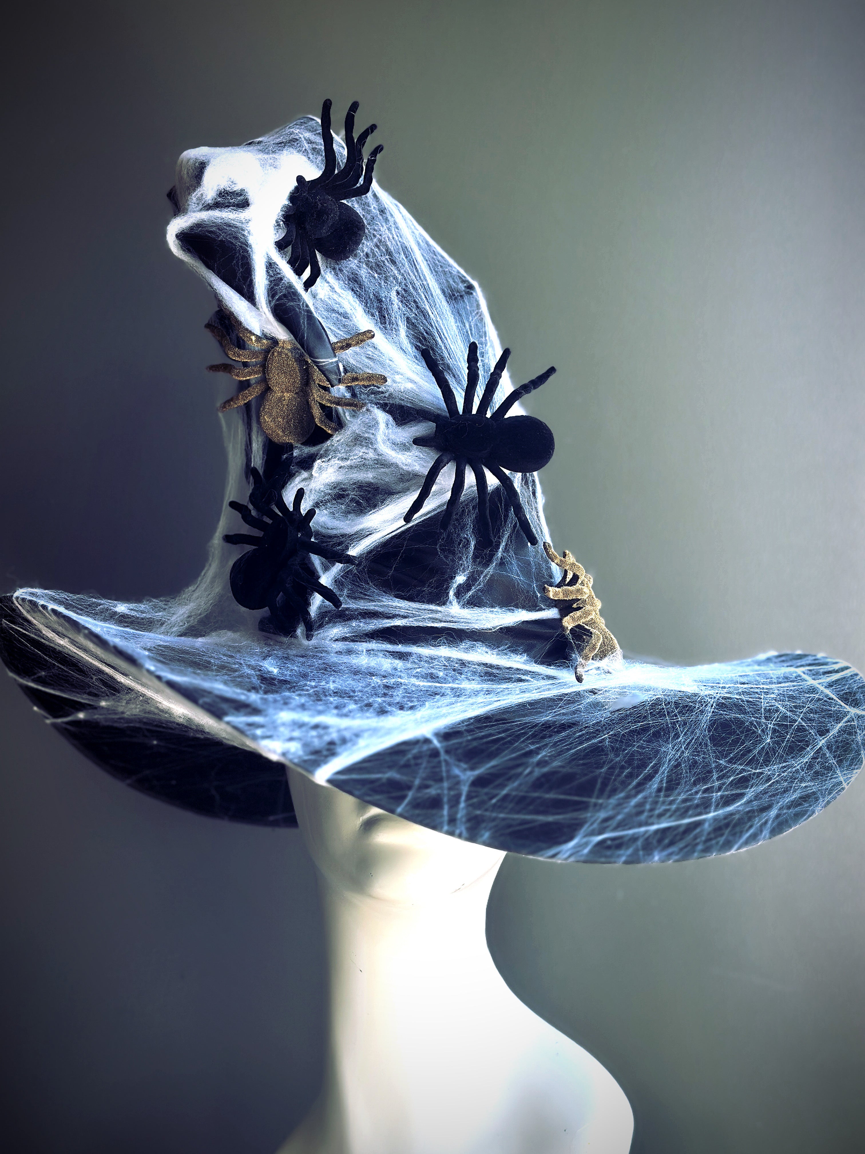 Black witch hat covered in spider webs and spiders.