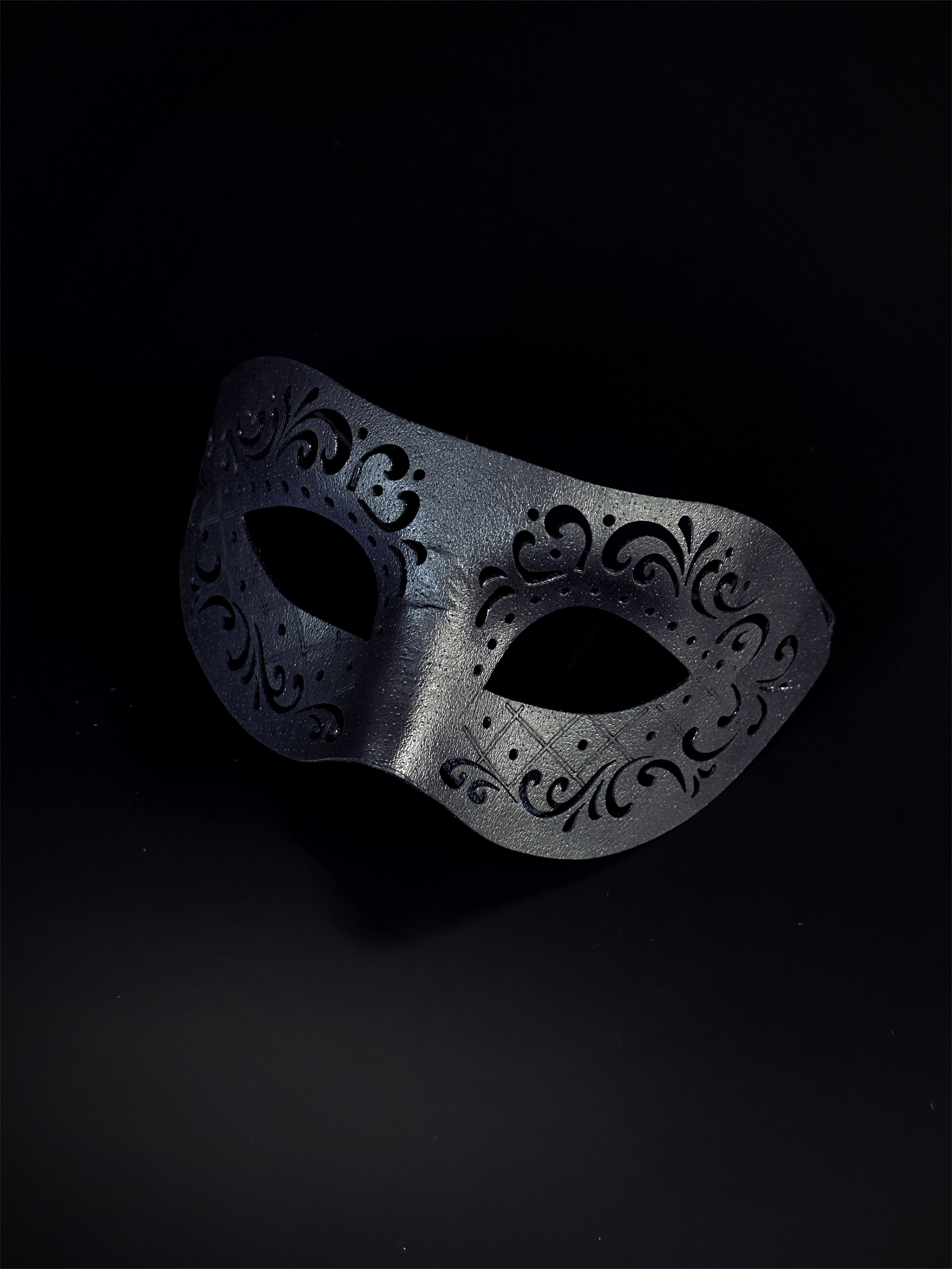 Black vegan leather masquerade mask with an engraved design.