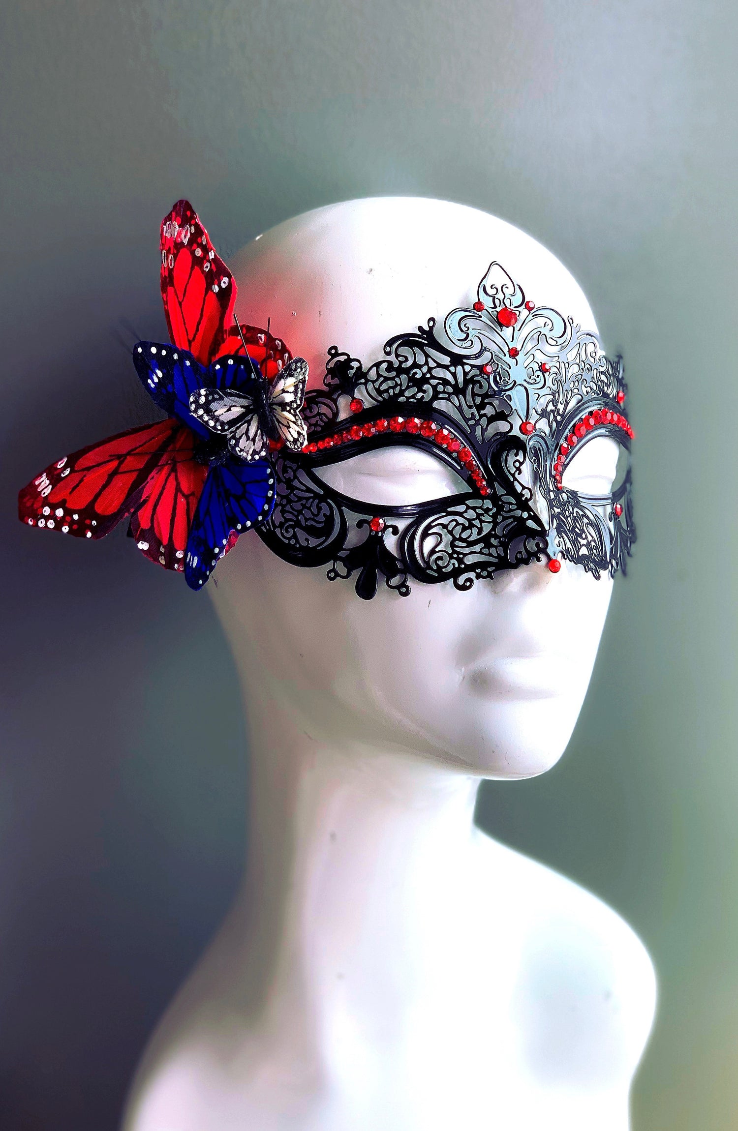 Black filigree metal mask with red, white, and blue butterflies, ideal for Fourth of July, patriotic events, and themed masquerade parties.