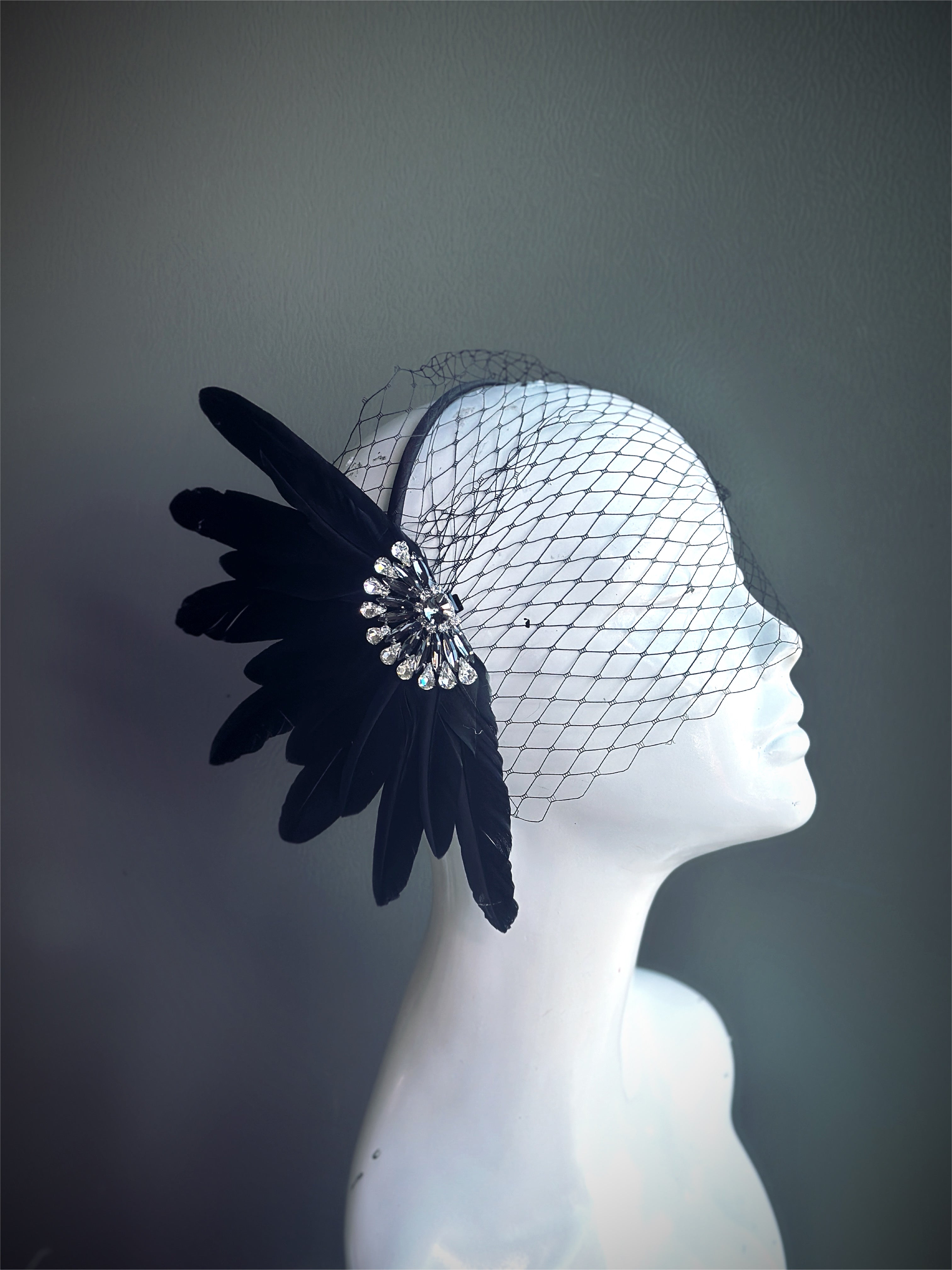 &quot;Black feather fascinator with a crystal accent and a delicate mesh veil, perfect for weddings and vintage-themed events.&quot;

