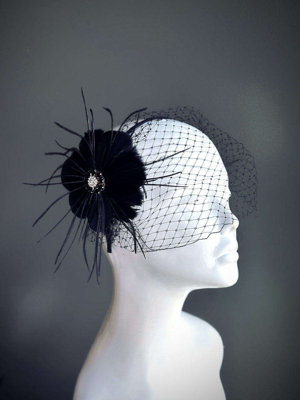 &quot;Black feather fascinator with a rhinestone center and a delicate mesh veil, perfect for weddings and elegant events.&quot;

