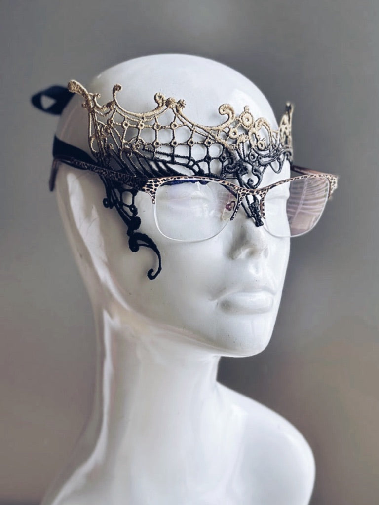 Black and gold masquerade mask designed for eyeglass wearers displayed on a white mannequin head.