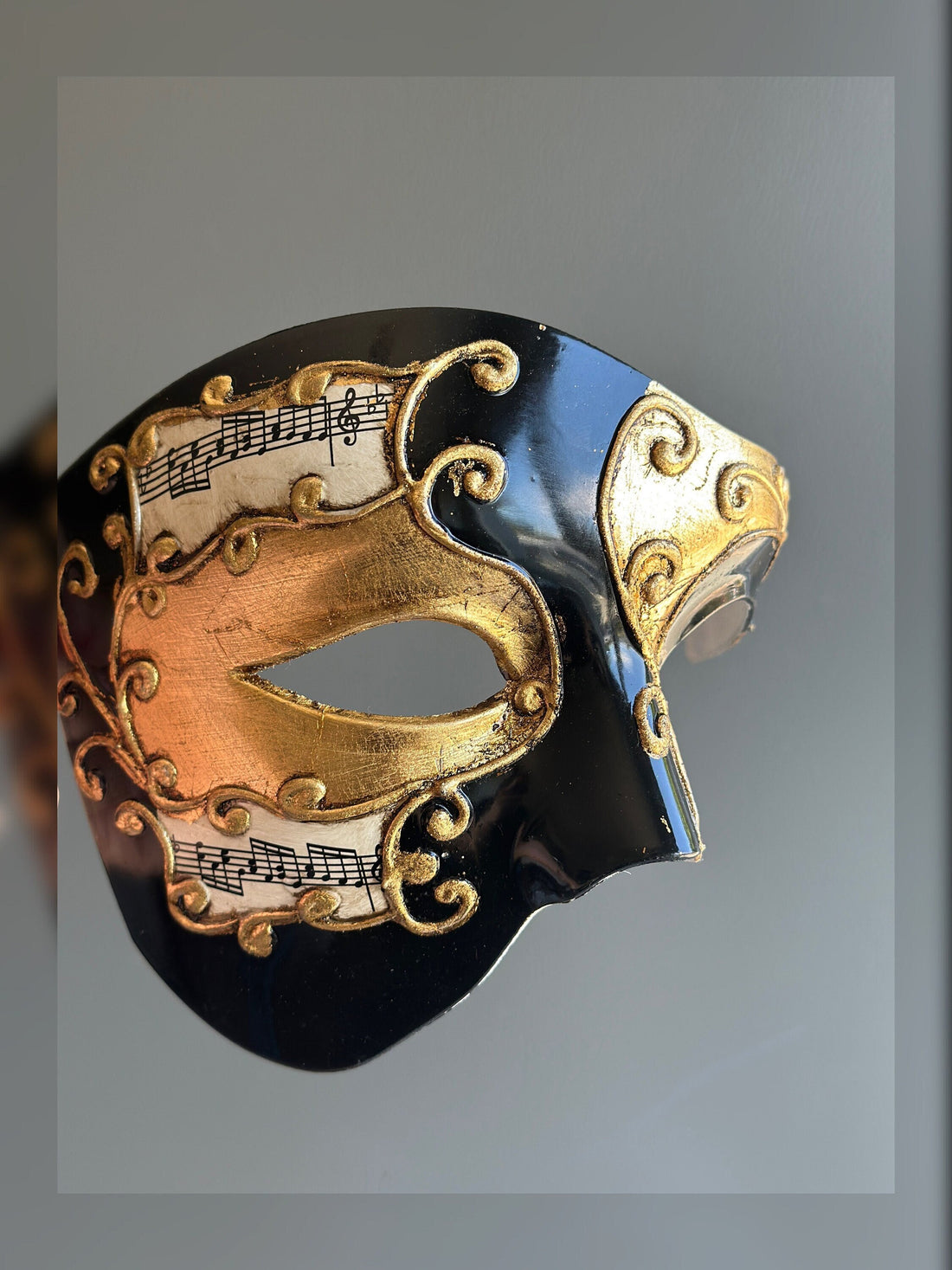 Black and gold Venetian-style mask with musical note accents and ornate detailing, ideal for elegant events and performances.