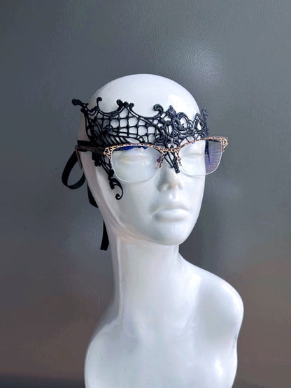 Black lace masquerade mask designed for eyeglass wearers displayed on a white mannequin head.