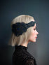 "Black headband with iridescent peacock feathers and intricate beadwork, perfect for masquerade balls or Gatsby-themed events."

