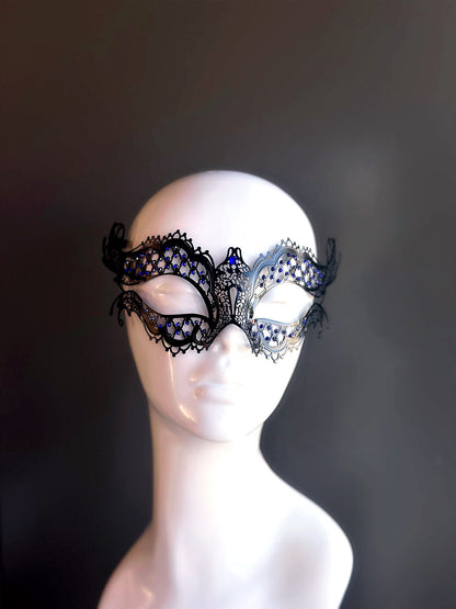 Black and silver metal mask with intricate cutouts and blue rhinestone accents for an elegant and sophisticated masquerade look.