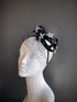 Black fascinator with rhinestone stars and a delicate veil displayed on a mannequin head.

