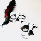 Day of the Dead couple’s mask set featuring skull designs with feathers and red accents