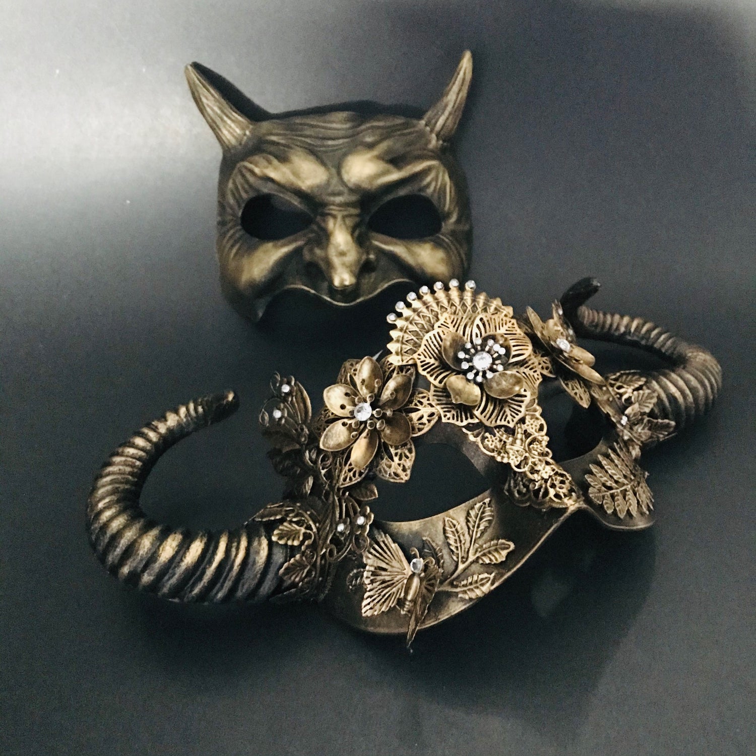 Devil’s Dance Gold Mask Set featuring a horned devil mask and a gold floral filigree mask.