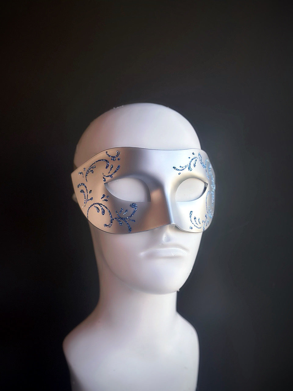 Silver mask with blue glitter swirl accents, featuring a frosted and sophisticated design for elegant occasions.