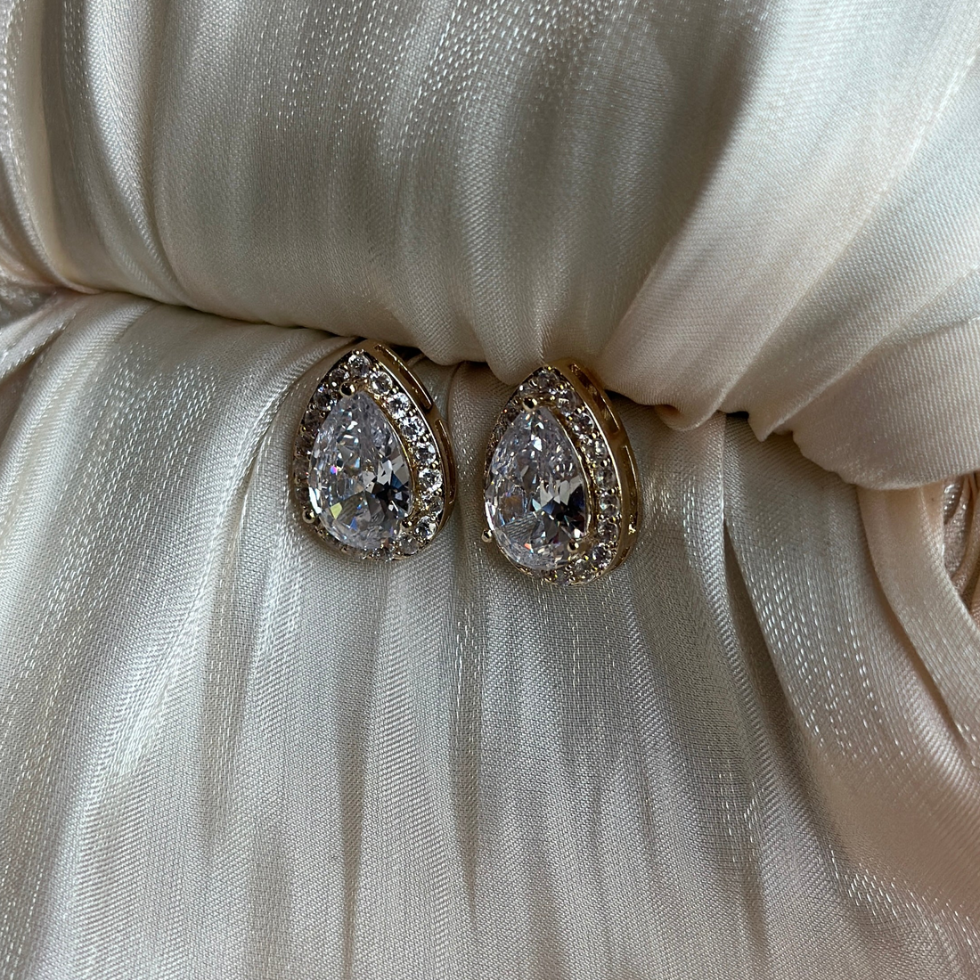 Gold earrings with teardrop-cut crystals encased in a double halo of shimmering stones.