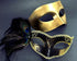 Gold Venetian mask paired with an ornate black mask featuring intricate details and a vibrant peacock feather, ideal for elegant occasions.