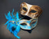 Gold and blue Venetian-style couple masks, one with ornate gold detailing and the other adorned with vibrant blue feathers, ideal for elegant events.