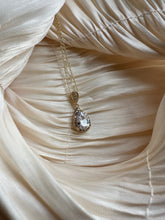 Gold necklace with a teardrop-cut crystal encased in a shimmering halo.