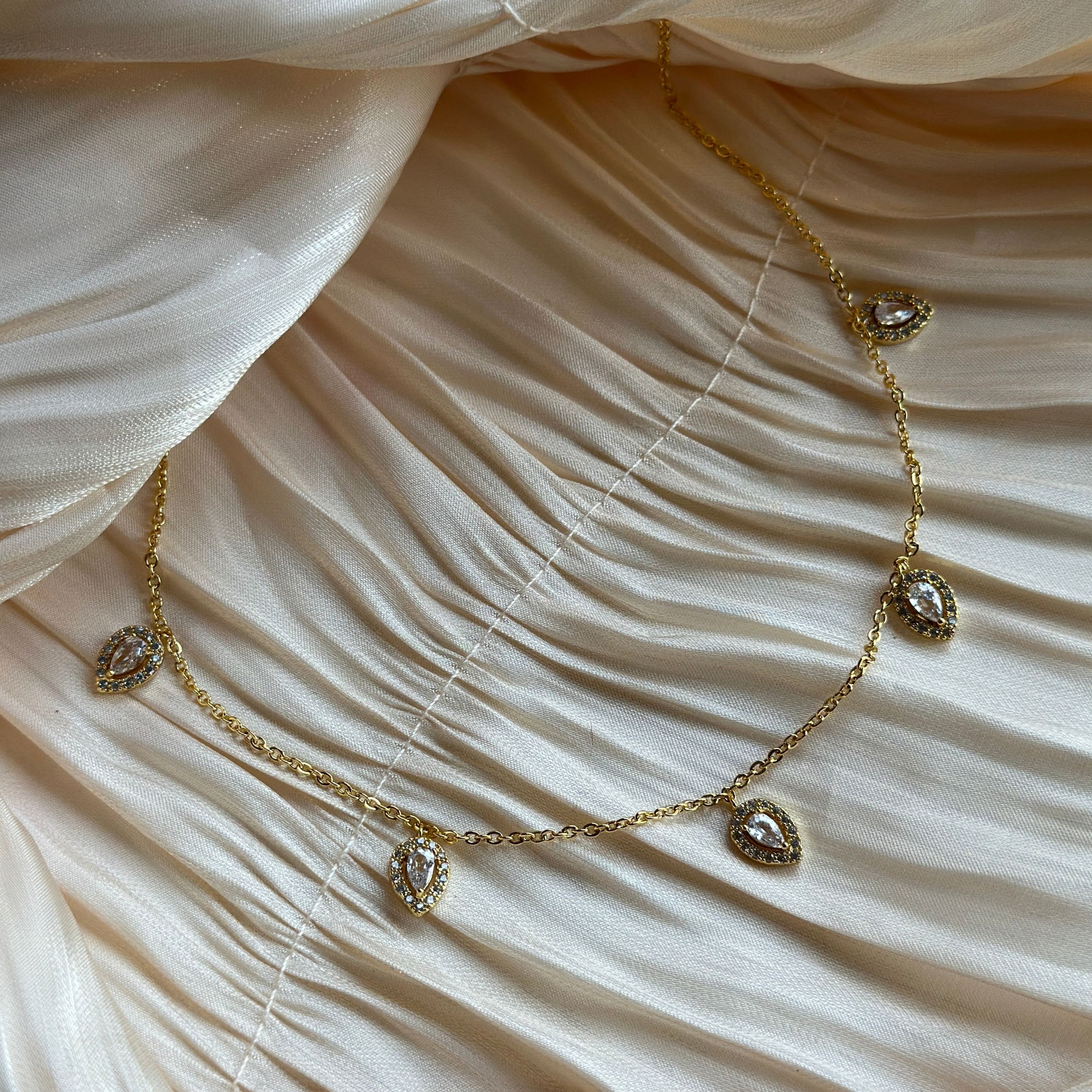 Gold necklace with teardrop-shaped crystal charms elegantly spaced along a fine chain.