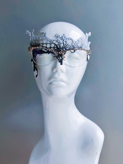 Gray lace masquerade mask designed for eyeglass wearers displayed on a white mannequin head.