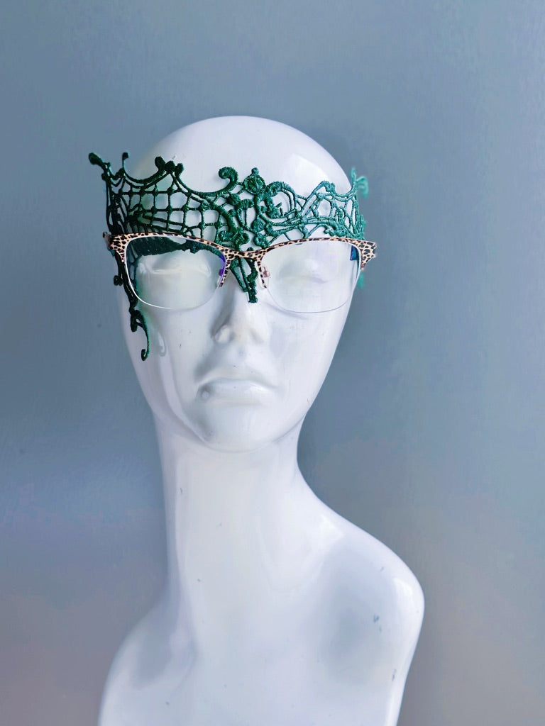 Green lace mask designed for eyeglass wearers on a white mannequin head