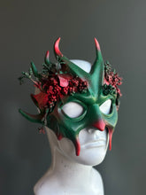 Green and red mask with festive forest-inspired details, including foliage and berries, ideal for holiday-themed events and parties.