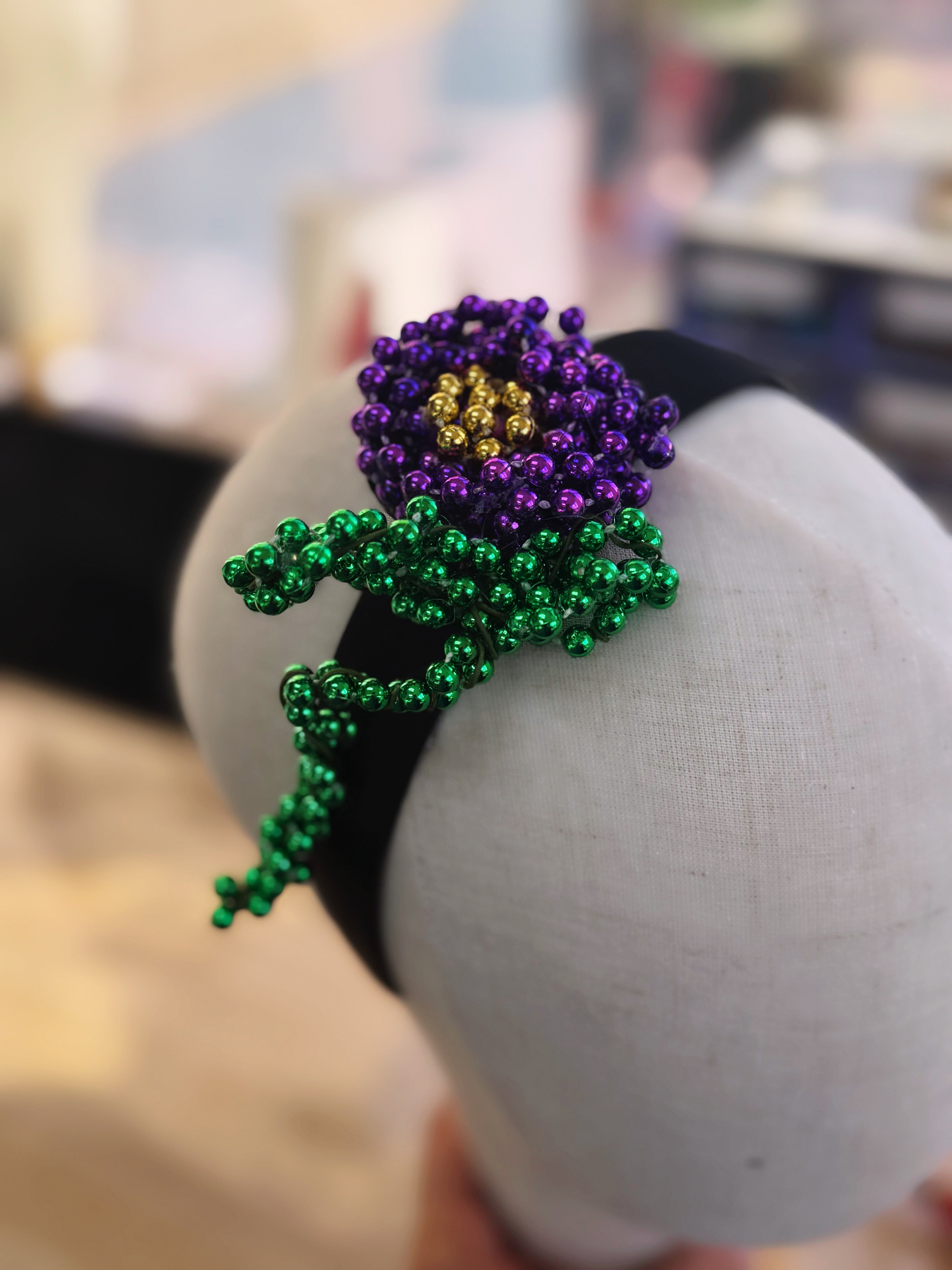 Mardi Gras headband with a handcrafted beaded flower in purple, green, and gold, designed for a festive and unique accessory.