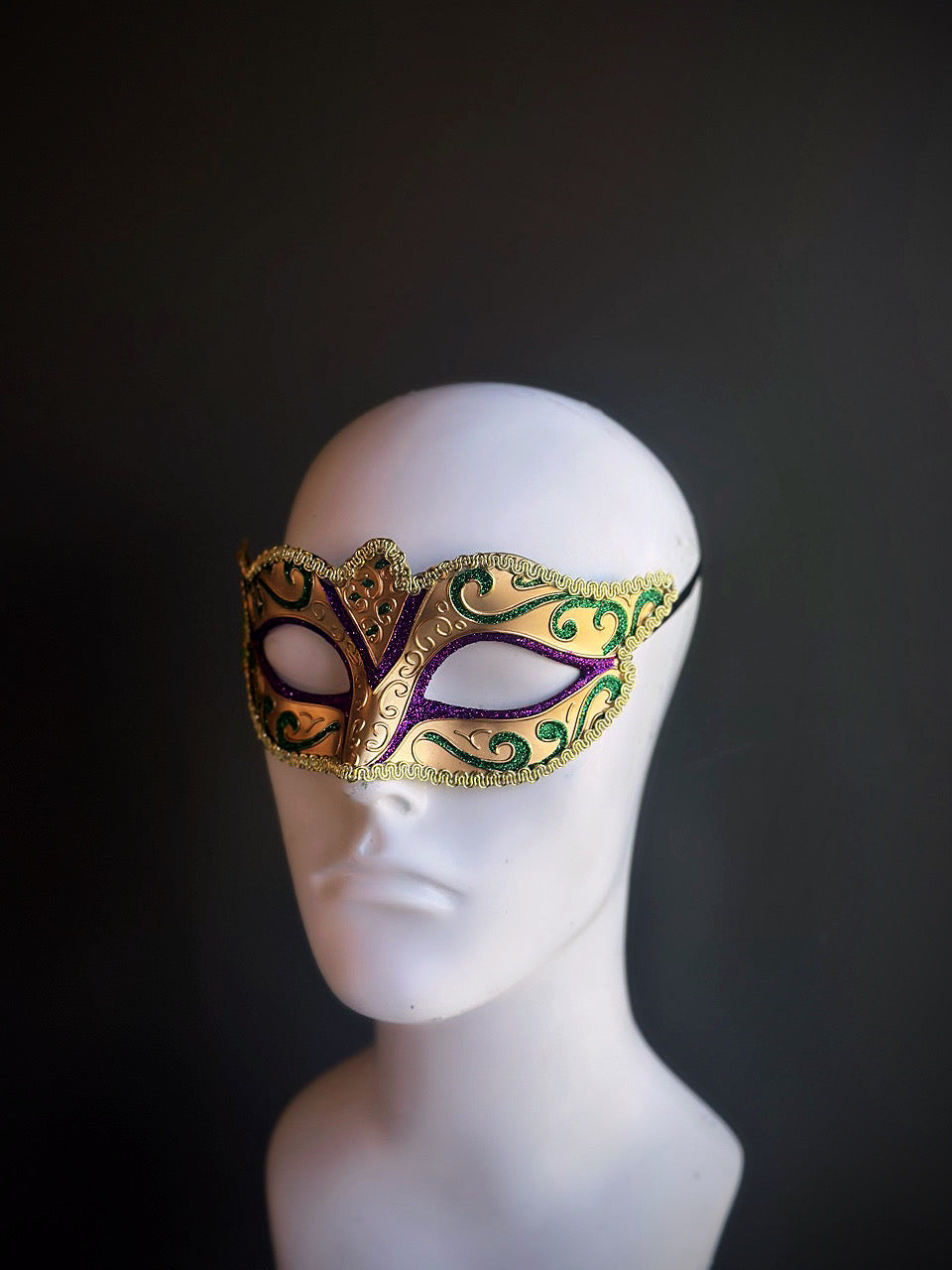 Mardi Gras mask featuring gold, purple, and green tones with intricate swirling details and a luxurious design.