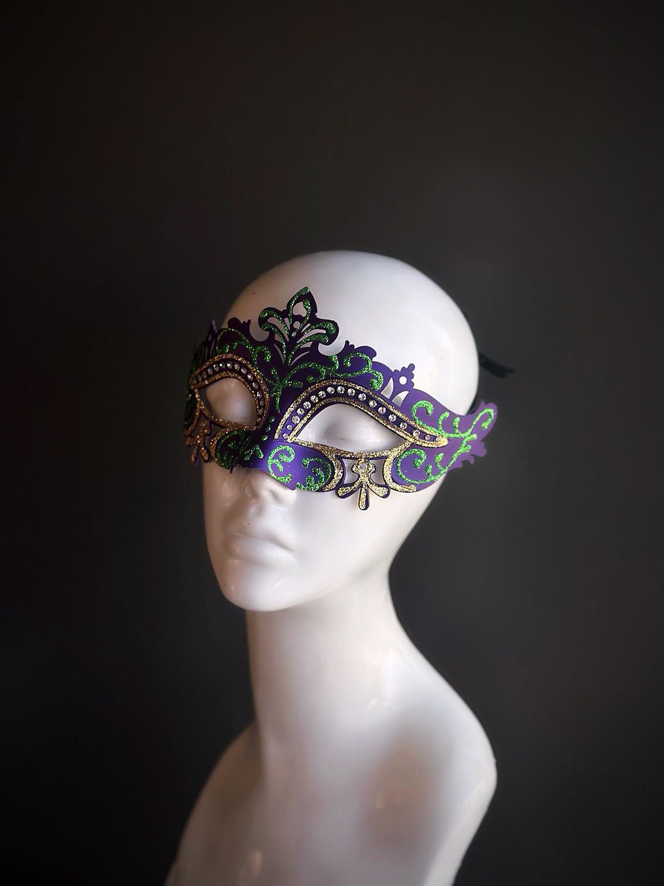 Purple and green Mardi Gras mask with gold filigree details and rhinestones, designed for a sophisticated and festive look.