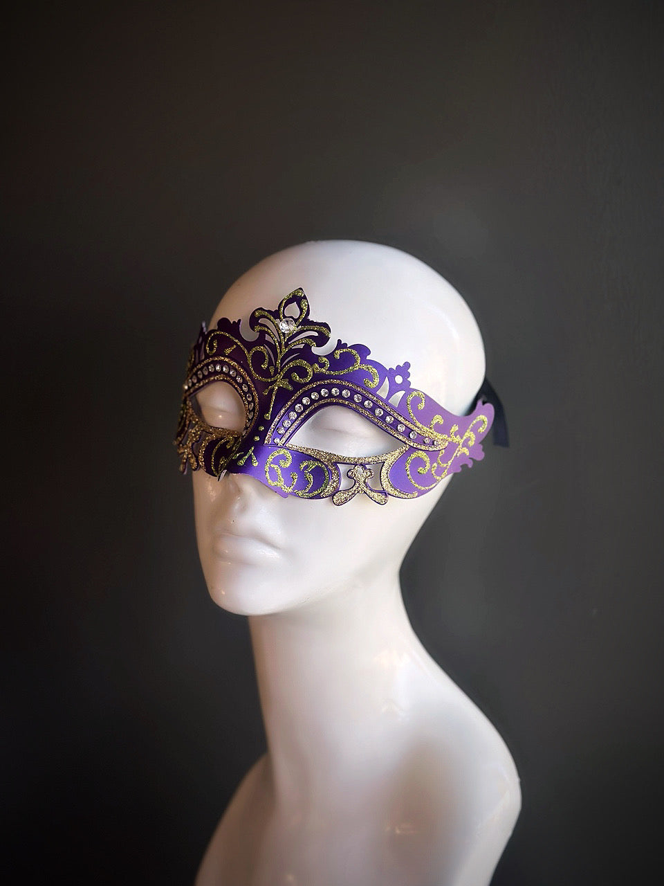 Purple and gold Mardi Gras mask with elegant green details, intricate design, and rhinestone embellishments for a luxurious touch.