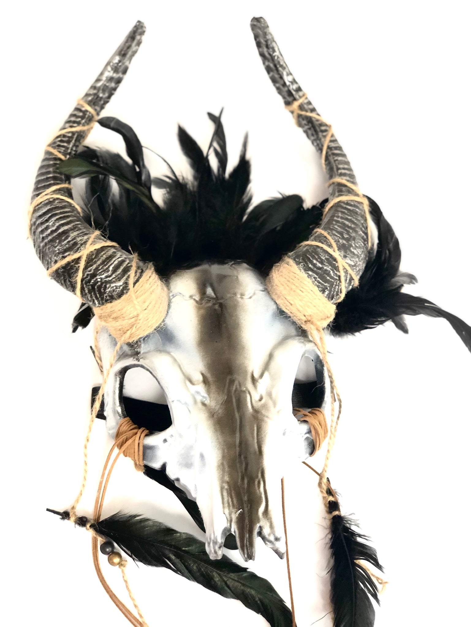 Norse shaman ram horn skull headdress with black feathers and rustic twine bindings.