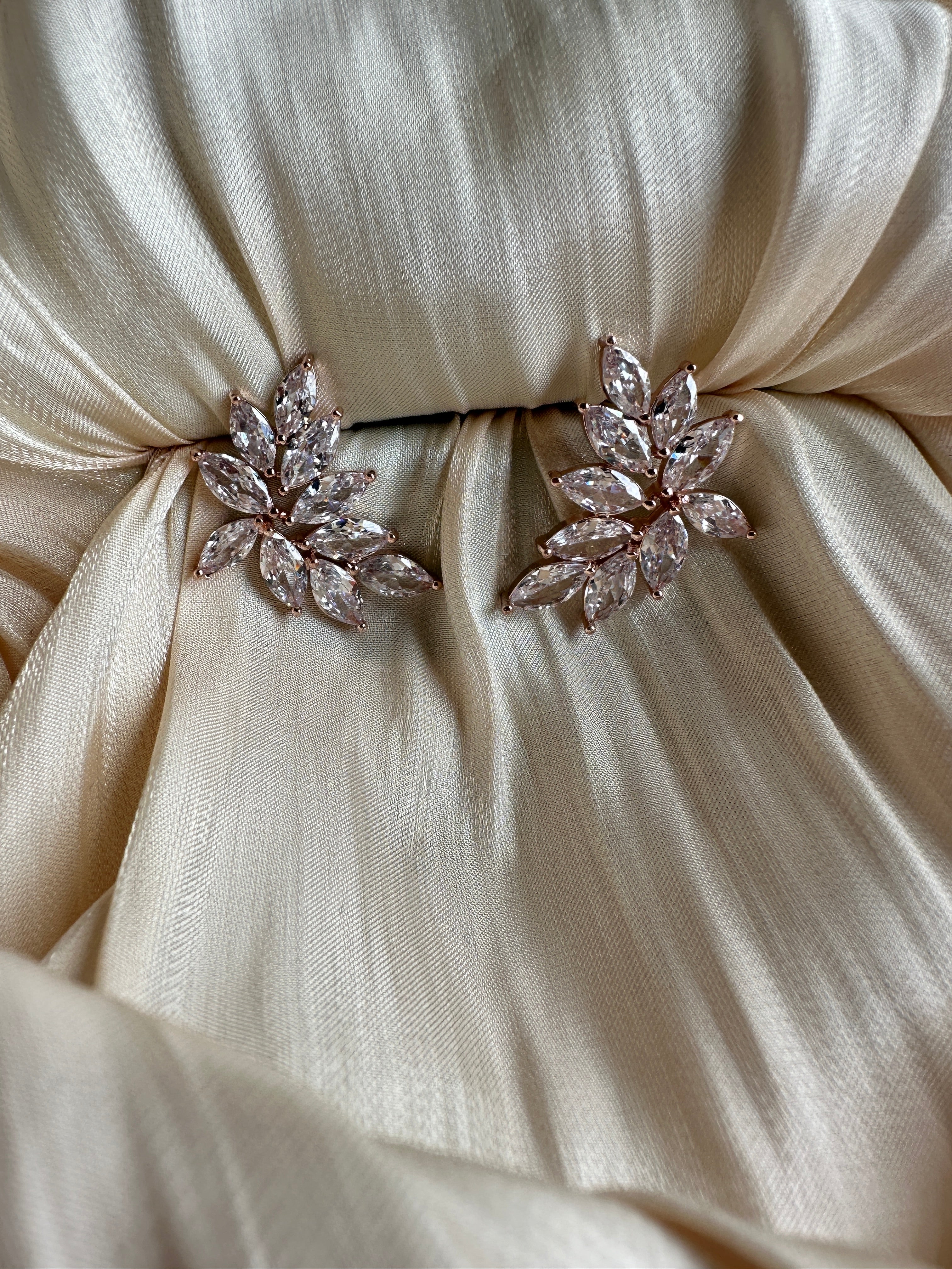 Rose gold earrings with marquise-cut crystals arranged in a cascading leaf design.