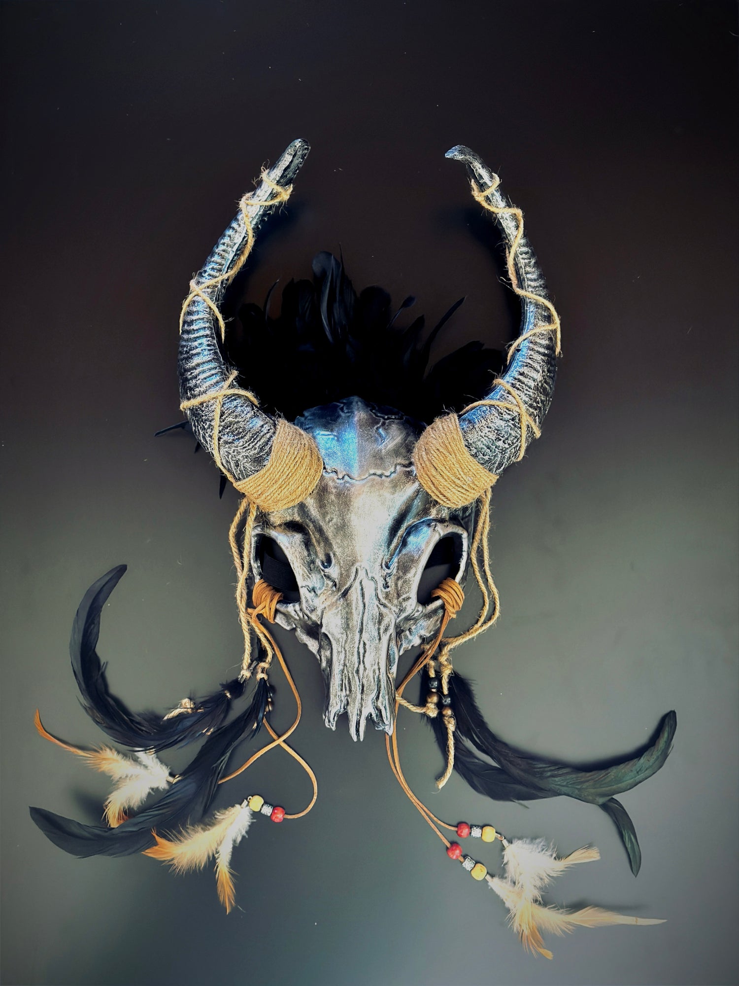 ram horn skull headdress featuring intricate hand-finished details, twine-wrapped horns, and ritualistic feather adornment