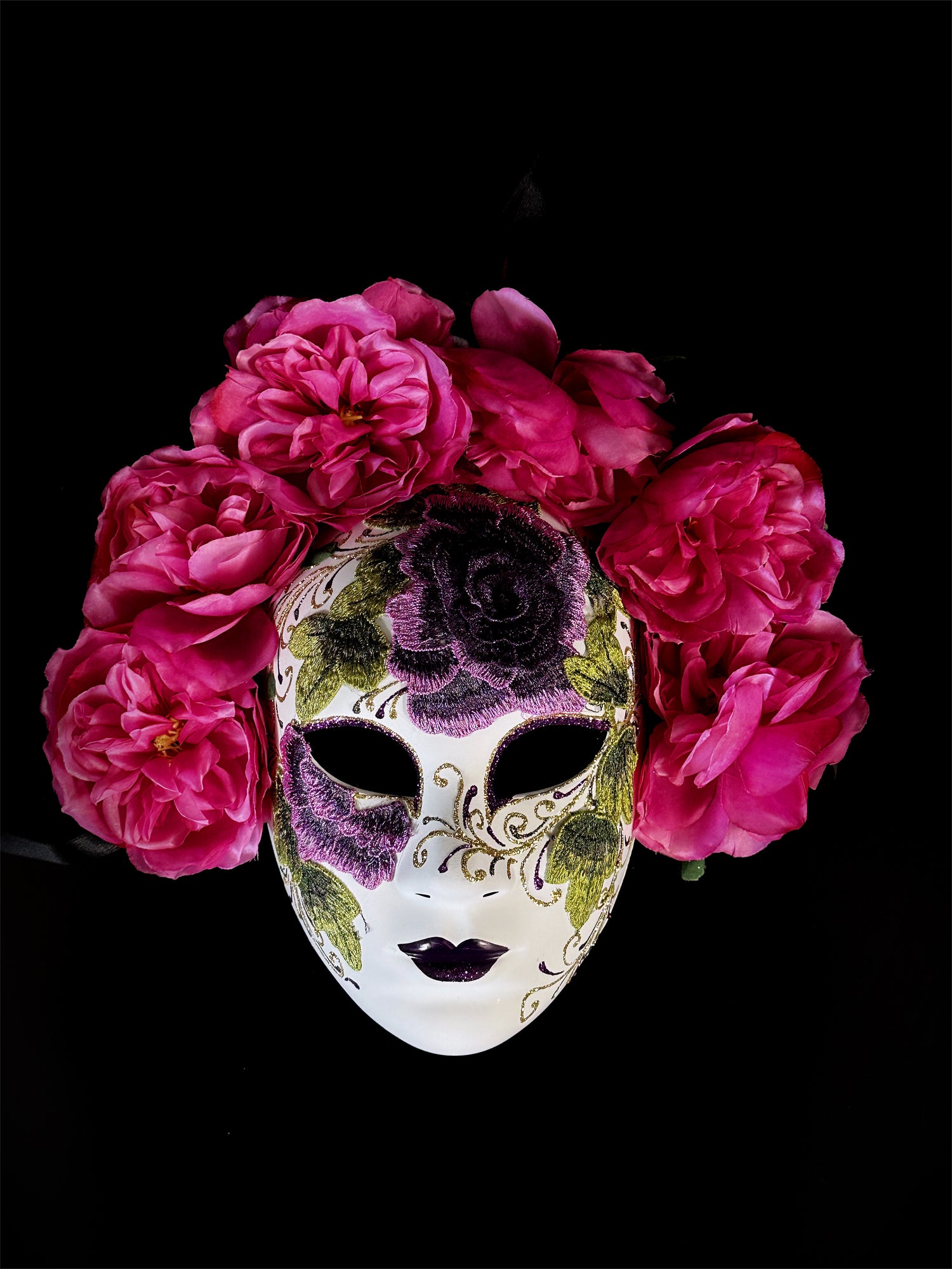 Pink floral mask with embroidered purple and green details, inspired by Venetian design, adorned with pink roses

