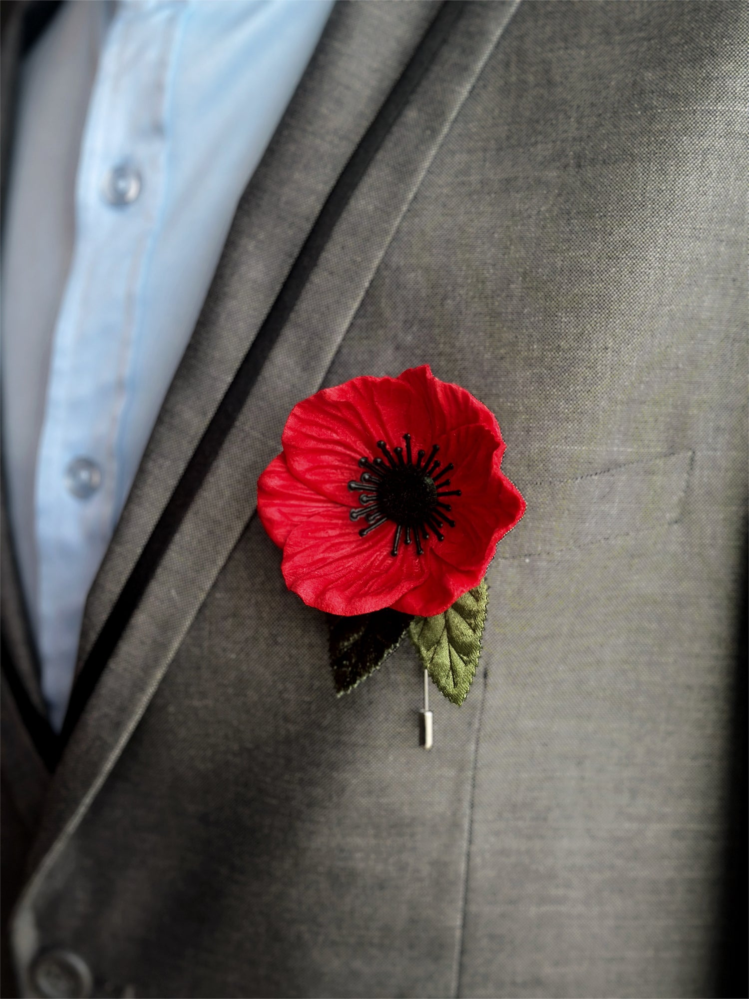 Red poppy lapel pin with black detailing, a stylish floral accent for prom and formalwear.