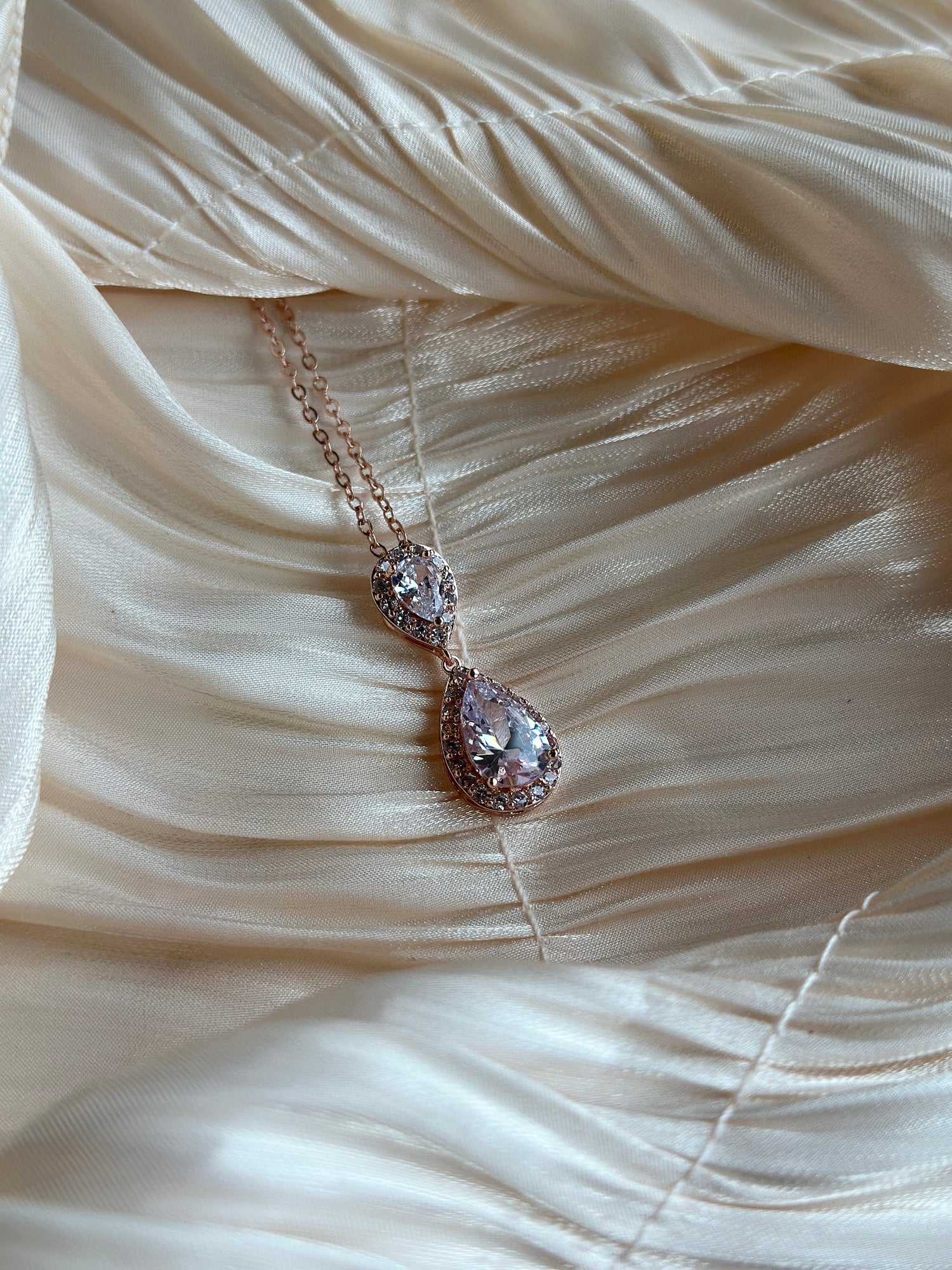 Rose gold necklace with two teardrop-cut crystals encased in a shimmering halo.