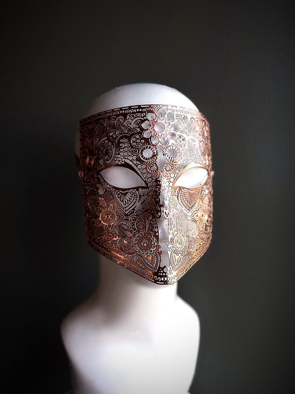 Rose gold full-face mask with intricate lace-like details and floral patterns, ideal for elegant occasions and themed events.