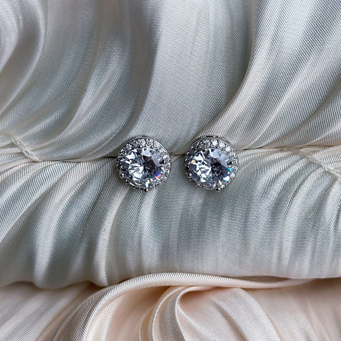 Silver earrings with round-cut crystals surrounded by a halo of sparkling stones.