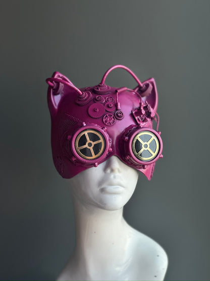 Pink steampunk cat mask with gear embellishments and metallic goggles, perfect for cosplay, festivals, and sci-fi events.