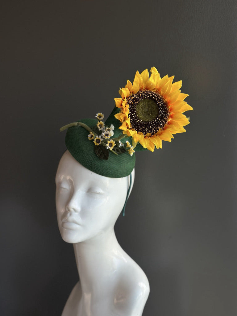 Elegant green fascinator with a bright sunflower and small floral details, ideal for derby events, garden parties, and summer celebrations.