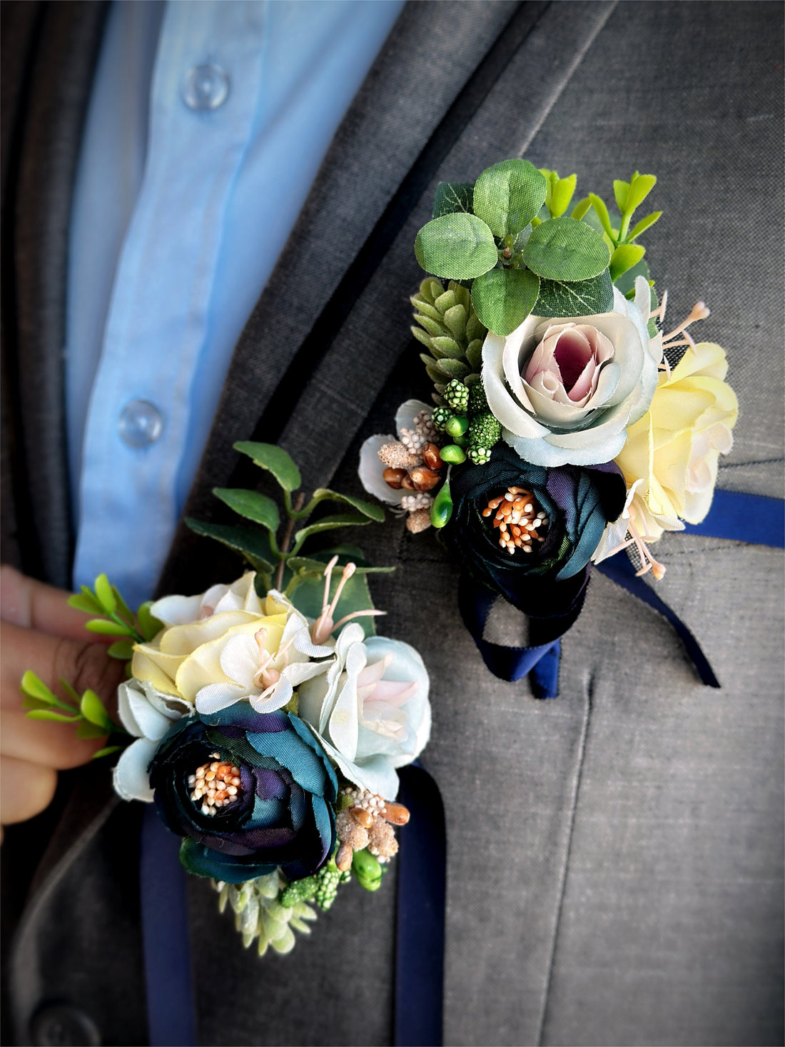 Indigo and ivory prom boutonniere and corsage set with lush greenery and delicate floral accents.