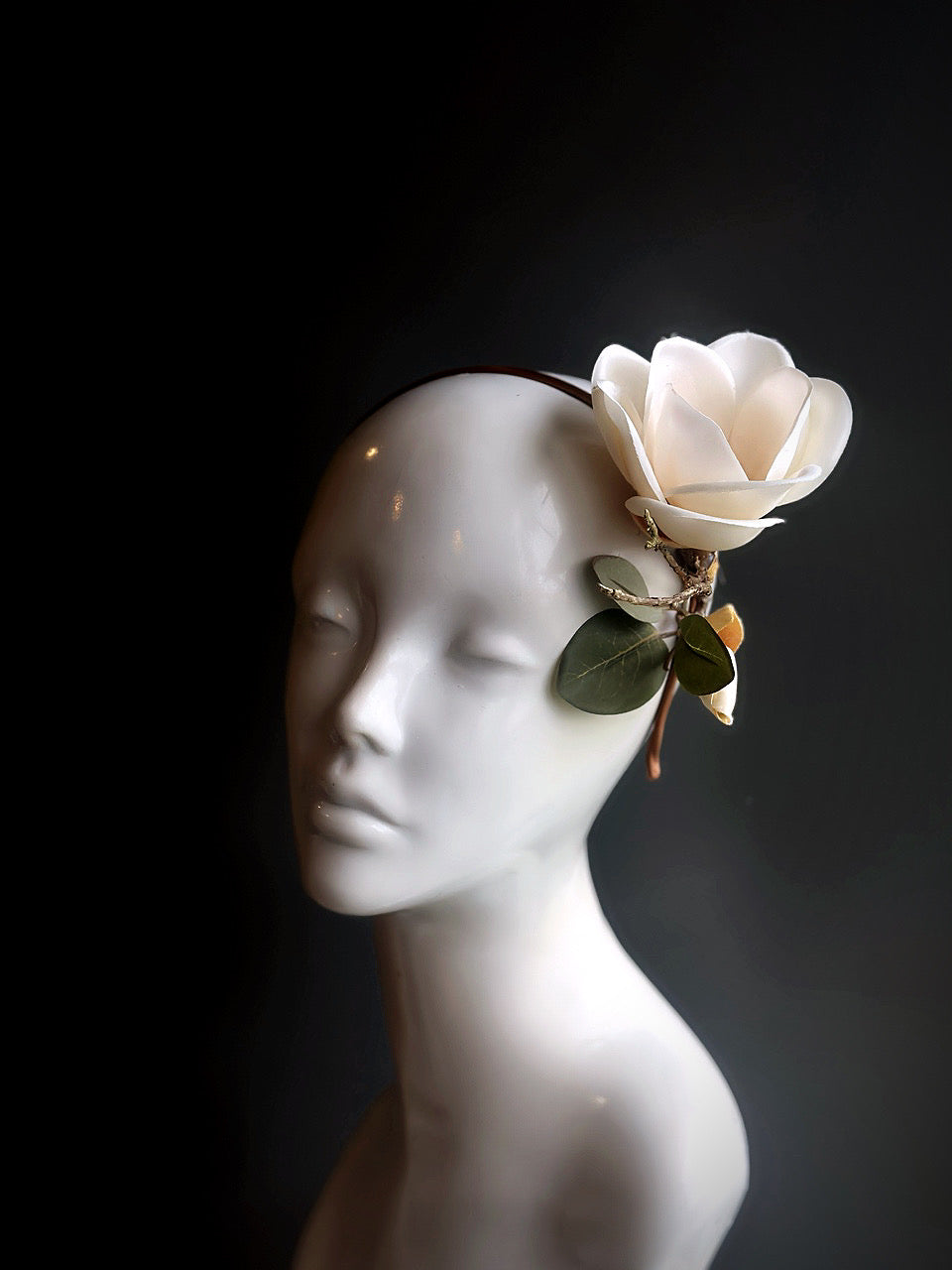  White magnolia fascinator with delicate leaves, designed for weddings, garden parties, or formal occasions.