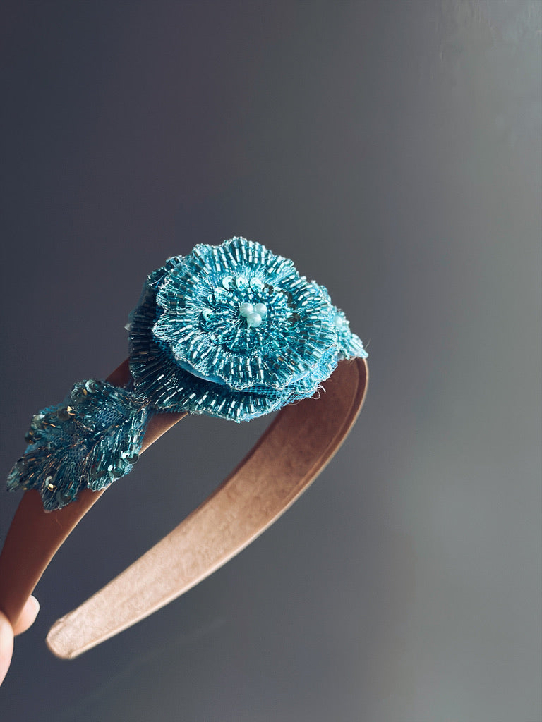 Teal embellished headband with a floral motif, ideal for winter celebrations and holiday events.