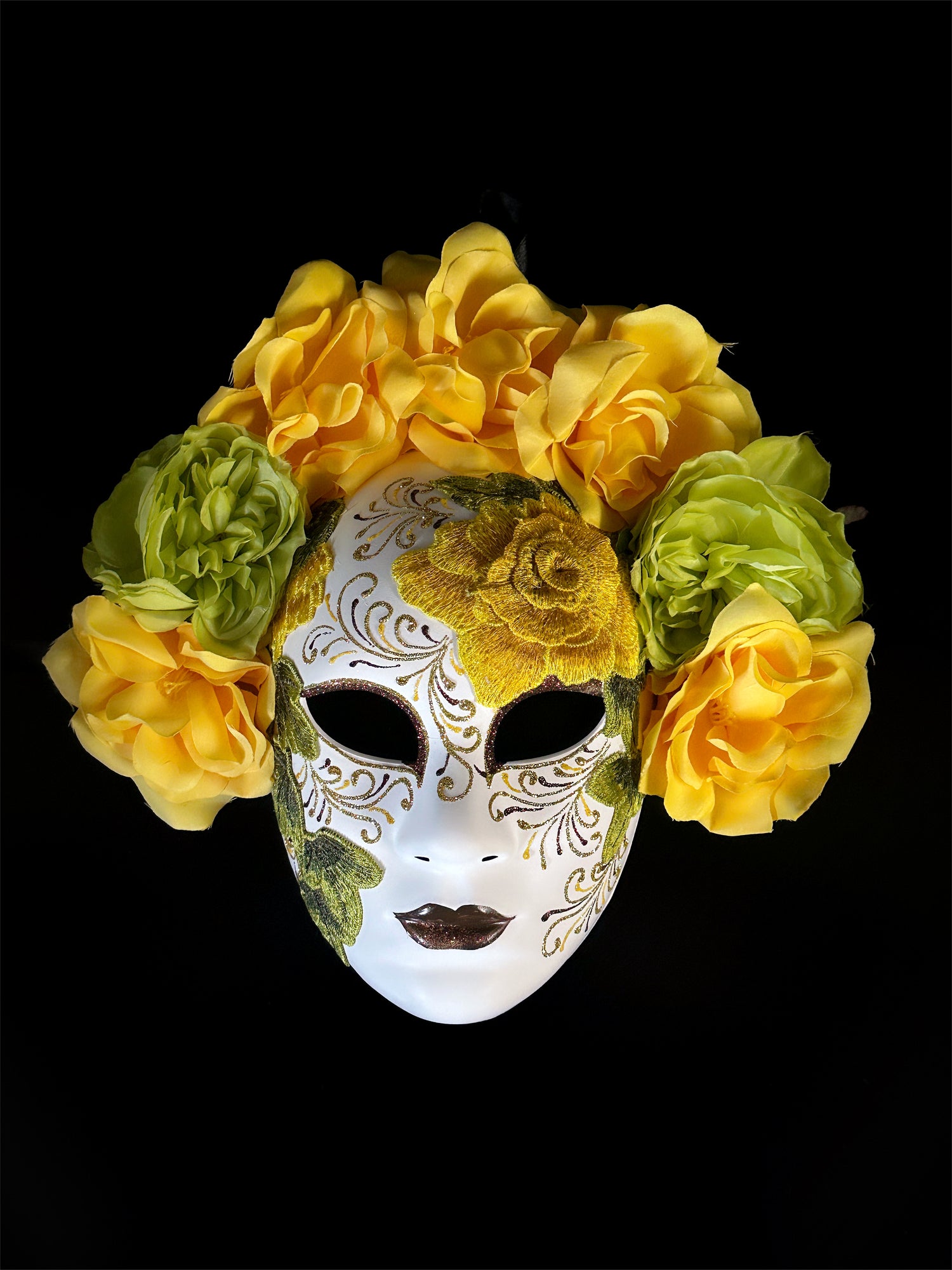 Yellow floral mask with embroidered details, inspired by Venetian style, featuring bold yellow and green flowers

